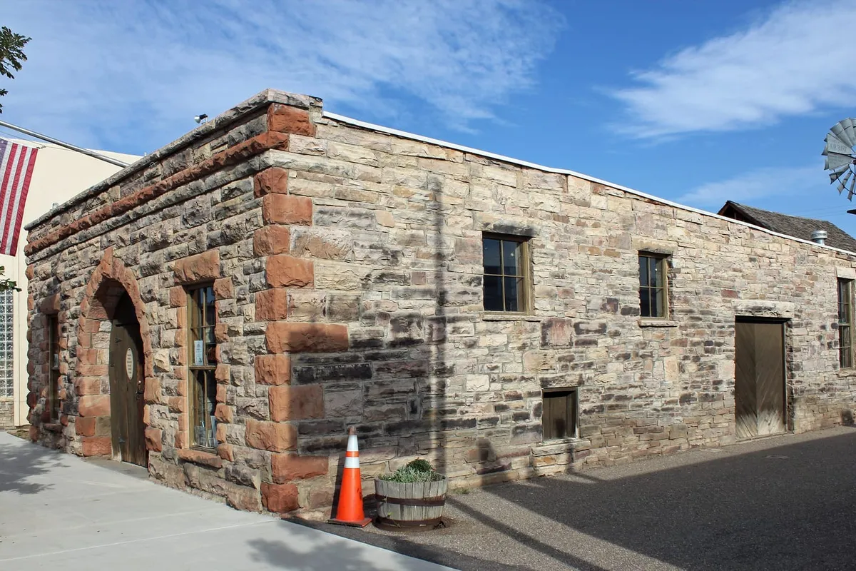 The stone Bimson Blacksmith Shop at the Pioneer Museum, with a windmill behind it