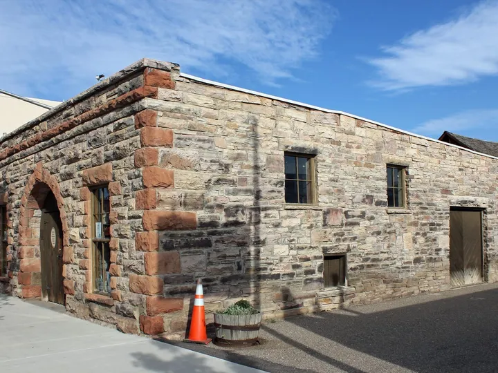 The stone Bimson Blacksmith Shop at the Pioneer Museum, with a windmill behind it