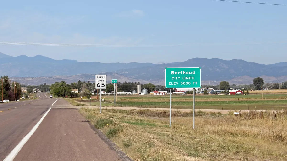 The Berthoud town-limits sign on the road in from the east, with the plains behind it
